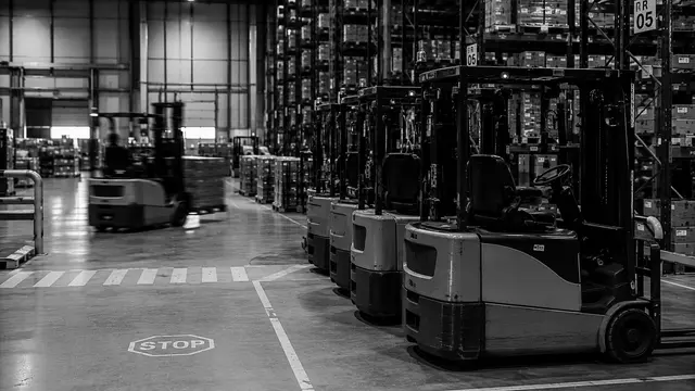 Row of forklifts parked side by side in a warehouse