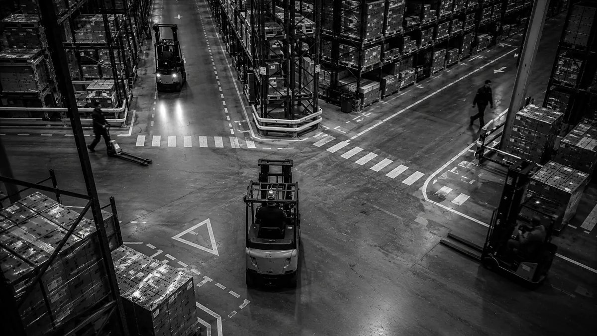 Forklift in a narrow aisle with damaged racking in a warehouse