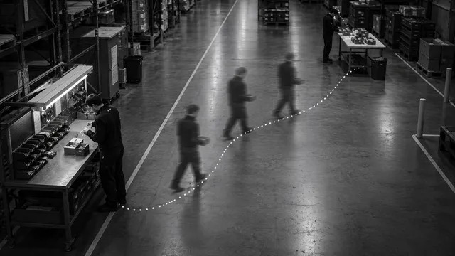 Employee at an assembly bench with a dotted line showing the walking route to a table further away