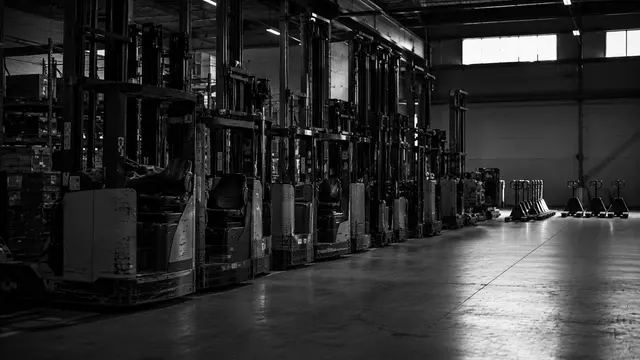 Forklifts parked in a warehouse, partly unused