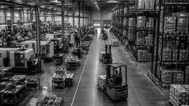 Gecombineerde hal met machines aan de ene zijde en palletstellingen aan de andere, met heftrucks ertussen