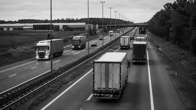 Vrachtwagens op een snelweg langs een logistiek bedrijventerrein richting de grens